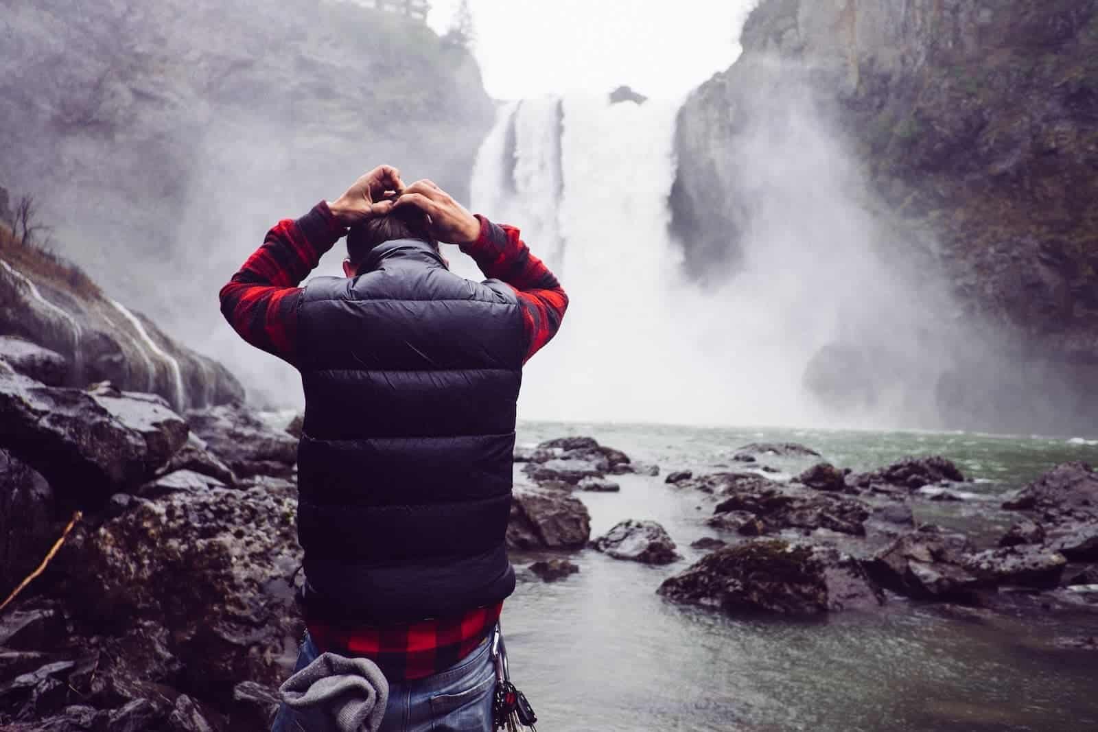 Dramatic man holding head at waterfall
